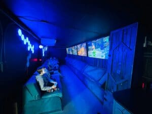 A man sitting on top of a couch in front of two large screens.