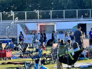 A group of people sitting in lawn chairs next to an outdoor stage.